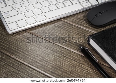 Notepad, keyboard, mouse and cellphone on wood table