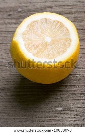 half of sour yellow lemon laying on the old wooden table vertical