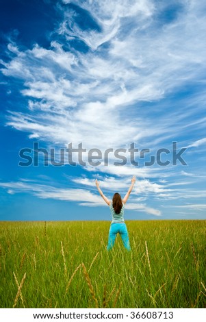 woman rising up hands on green field