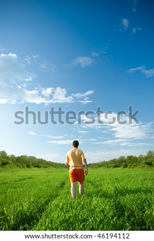 man walking away trough the green field