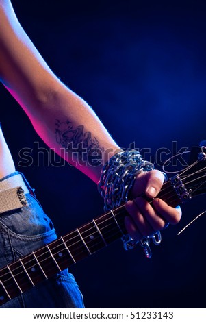 closeup man hand with tatoo and chain holding guitar