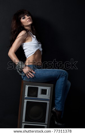 beautiful garage style woman sitting on speaker near black wall
