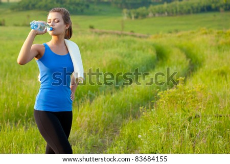 sport woman drinking water on field