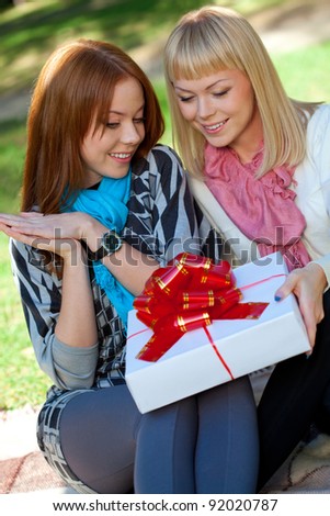two sisters with gift sitting in the summer park
