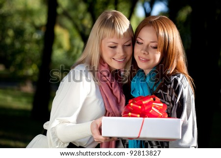 two beautiful sisters with gift in the summer park