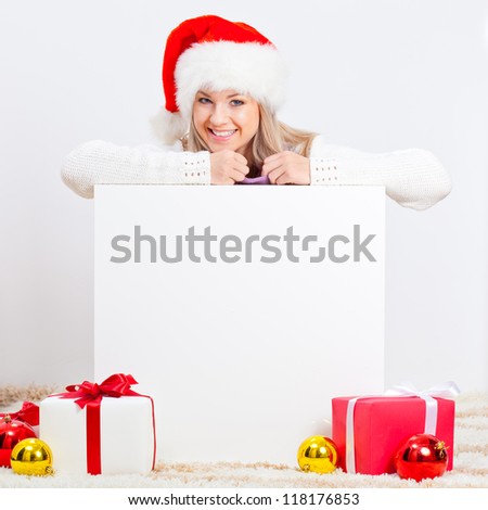 blonde woman wearing santa hat sitting on the floor behind white blank board