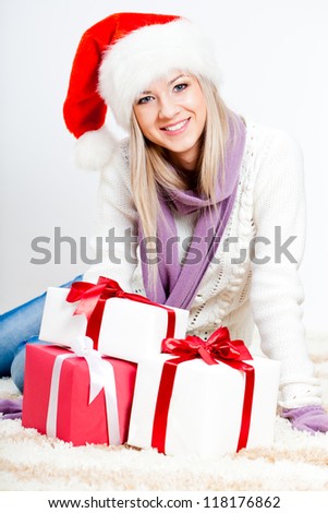 blonde woman wearing santa hat sitting on the floor with gifts
