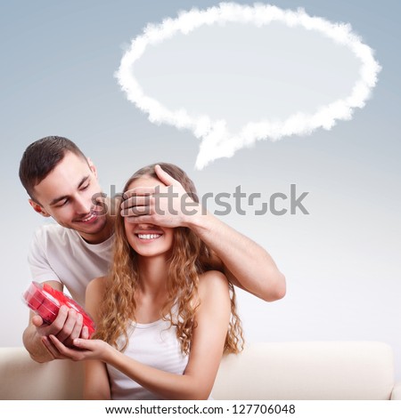 young man gives his girlfriend a heart-shaped box, he covered her eyes with  hand, girl dreaming with balloon