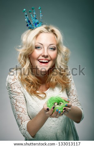 emotional portrait of woman wearing  blue princess crown and holding nest with quail eggs
