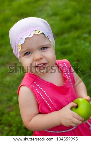 cute little girl walking in the park with green apple, top point of view