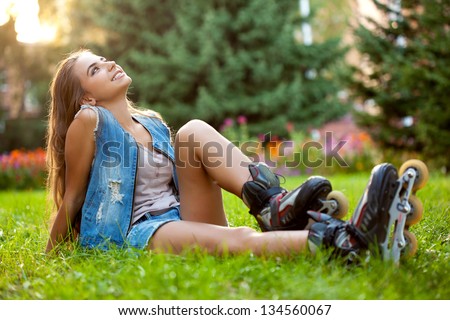 girl wearing roller skates sitting on grass in the park
