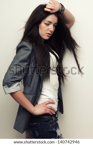 sexual woman fashion studio portrait with flying hair over white wall, holding hand over head