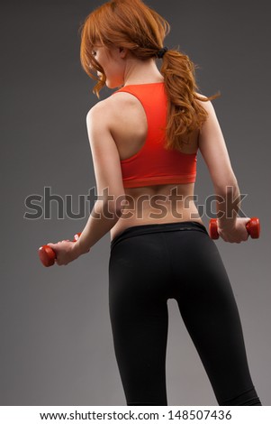 red -haired woman exercising with red dumbbells