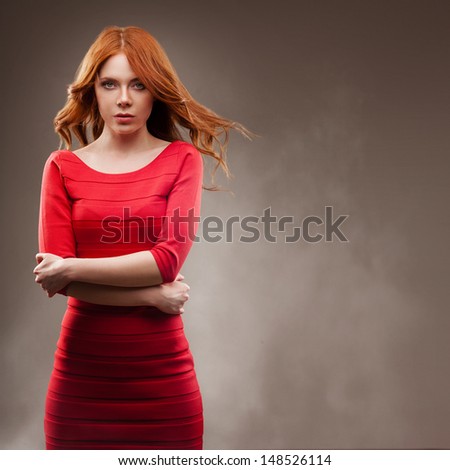 sexual woman portrait with flying hair wearing red dress over dark background, copy space