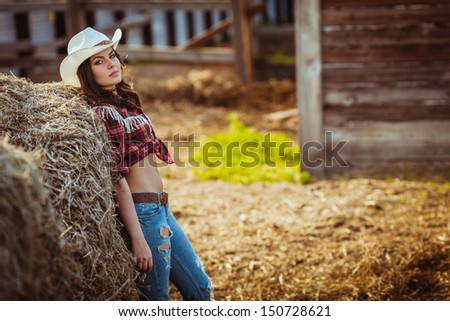 beautiful cowgirl style model posing on farmland, copy space