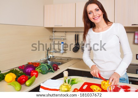 Smiling young housewife mixing fresh salad