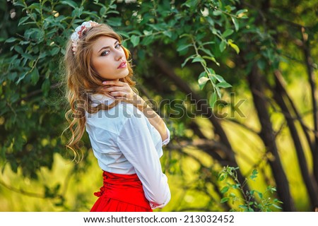 Romantic portrait of the woman in red skirt standing under the tree