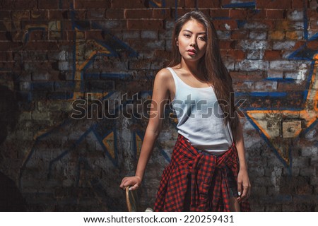Beautiful asian teen girl with skate board. Outdoors, urban lifestyle.