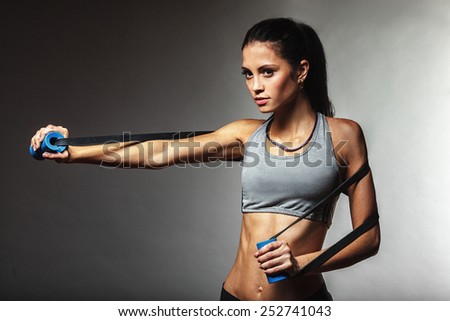 brunette athletic woman exercising with rubber tape