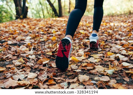 athlete woman runs for fall foliage, shoes closeup, back view