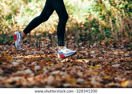 athlete woman runs for fall foliage, shoes closeup, motion blur effect