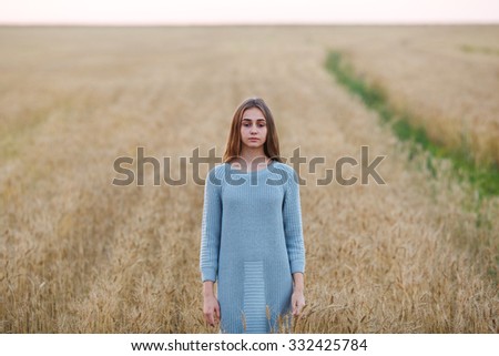 beautiful blonde fashion girl posing in wheat field at sunset, wearing knitted dress, static pose