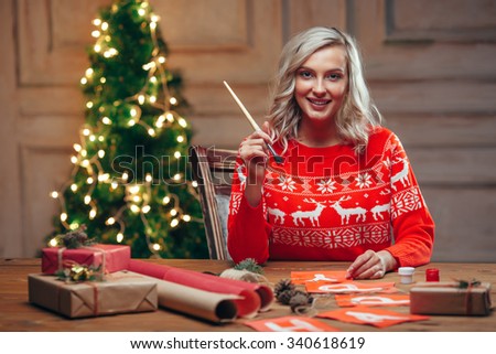 woman painting christmas flags with brush looking at camera, rustic style