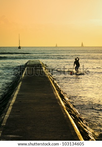 A silhouette of a man stand-up paddling at sunset in Waikiki, Hawaii.