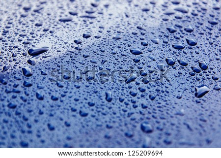 water beads on the hood of a blue car.