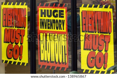 signs promote a giant sale as a store clears inventory before the location closes for business.