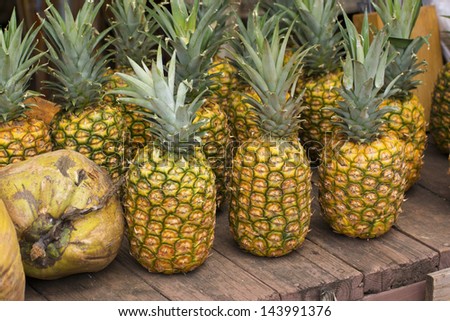 Hawaii, Oahu, Pineapples and coconuts for sale at a local roadside fruit stand on the North Shore.