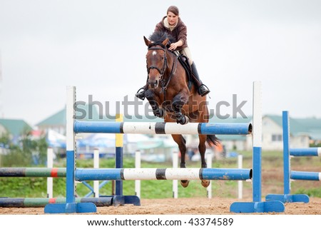 show jumping in rain - young girl and horse