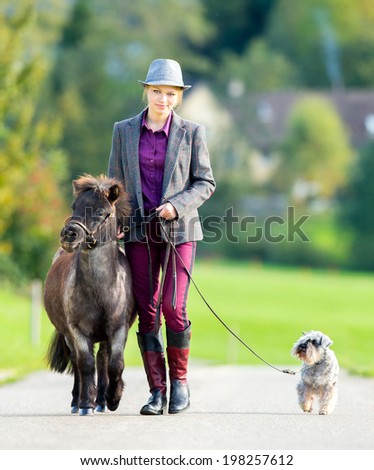Woman walking with pony and dog