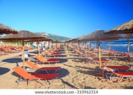 Rows of straw umbrellas and loungers at banana beach, Zakynthos, Greece.
