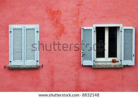 Two windows on a pink wall, one with white shutters closed