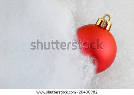 Close up of a red bauble in fluffy cotton with copy space and slight glow