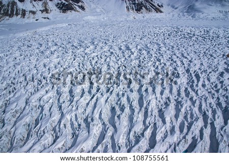 Aerial View of a Frozen River of Ice in the Great Alaskan Wilderness, Denali National Park, Alaska.  A Beautiful Snowscape of Rock, Snow, Water and Ice.  One of many glaciers flowing from mountains.
