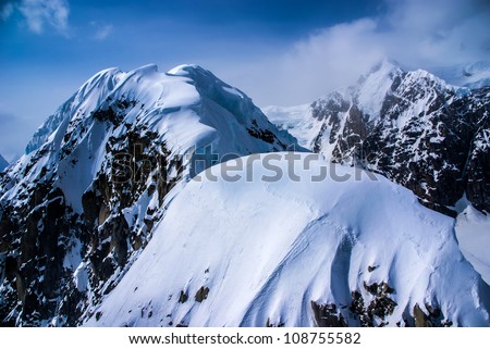 Closeup Aerial View of Snow Packed Craggy Mountain Tops in the Great Alaskan Wilderness, Denali National Park, Alaska.  Mount McKinley in background on right.  A Beautiful view of Rock, Snow and Ice.