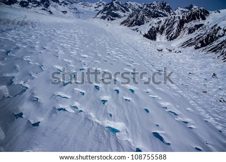 Aerial View of a Frozen River of Ice in the Great Alaskan Wilderness, Denali National Park, Alaska.  A Beautiful Snowscape of Rock, Snow, Water and Ice.  One of many glaciers flowing from mountains.