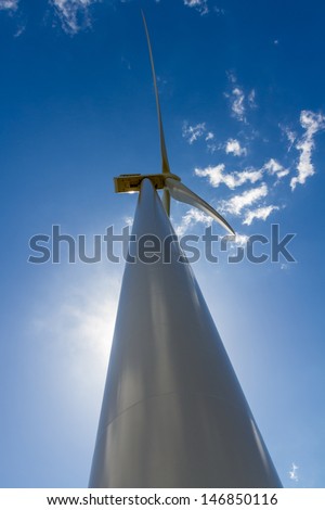 Unusual Angle Closeup of a Huge High Tech Industrial Wind Turbine Main Compartment While Generating Environmentally Sustainable Clean Electricity in Oklahoma.  With Blue Skies and White Clouds.