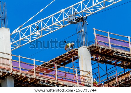 High-Rise Construction Job.  High altitude building assembly.  Concrete, steel, glass, and man in concert.