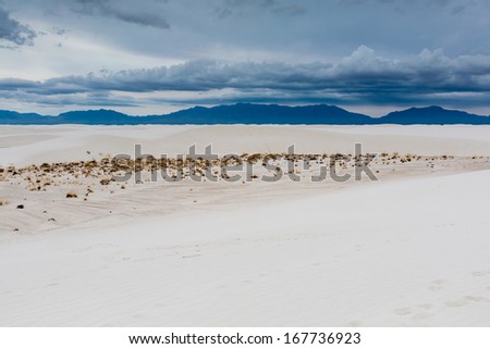 The Amazing White Sands with Cloudy Blue Skies of White Sands Monument National Park in New Mexico.  With Mountains in distance.