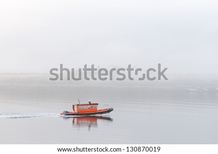 small orange boat sailing in fog