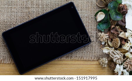 Dry flowers frame on wooden background with tablet computer (tablet pc)