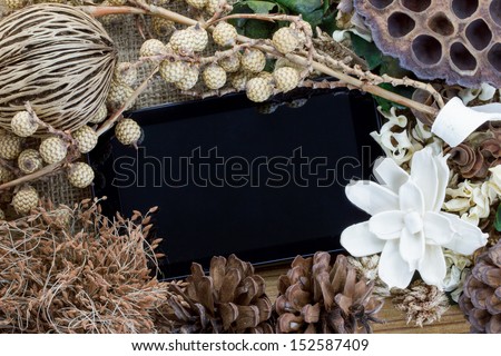 Dry flowers frame on wooden background with tablet computer (tablet pc)