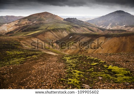 Volcanic landscape with moss and dramatic cloudy sky in Iceland