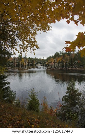 Autumnal tree branches overhang a calm body of water