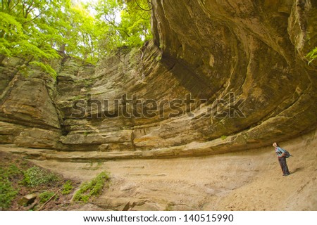Hiker gazing up at cliff overhang