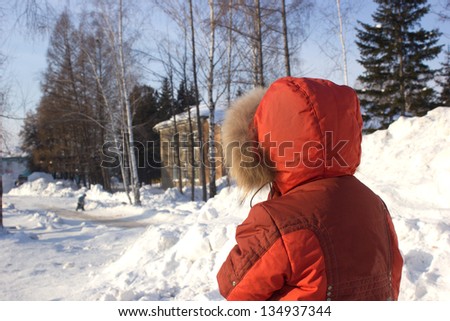 Boy standing near to ice hill watching other people playing