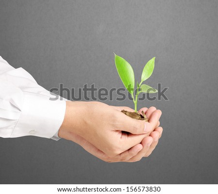 usinessman holding plant sprouting from a handful of coins